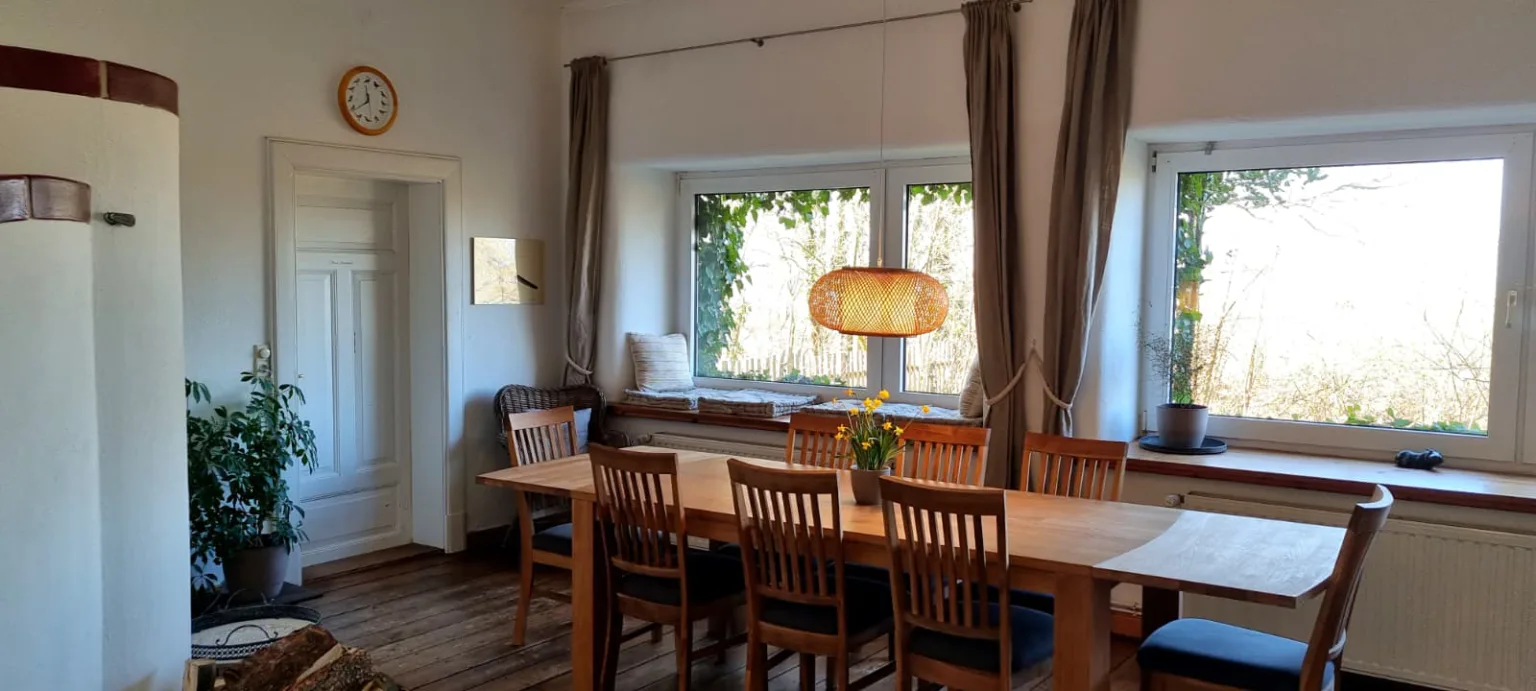 Esszimmer mit langer Holztafel, Kachelofen und Fensterbank